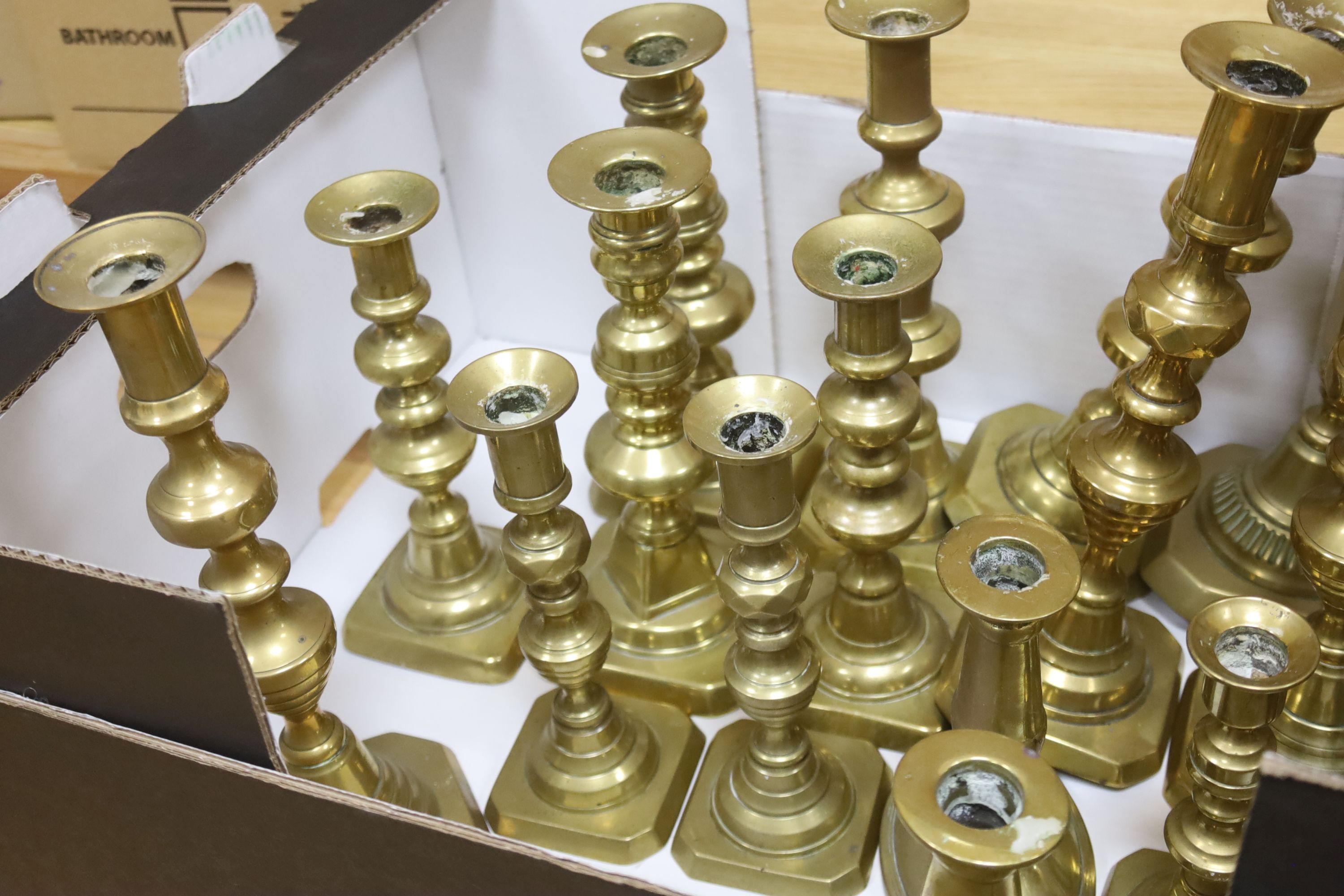 A large canteen of various brass candlesticks, mostly 19th century